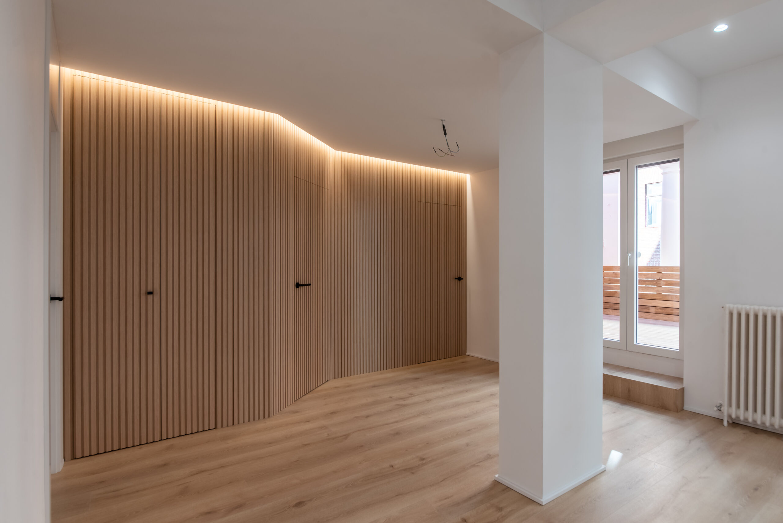 Armarios empotrados de madera con iluminación y suelo claro.