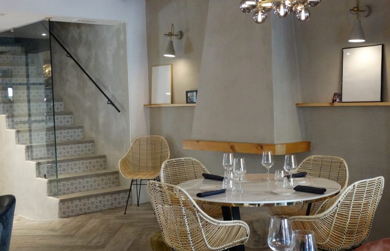 Interior moderno de restaurante con mesa y escalera decorativa.