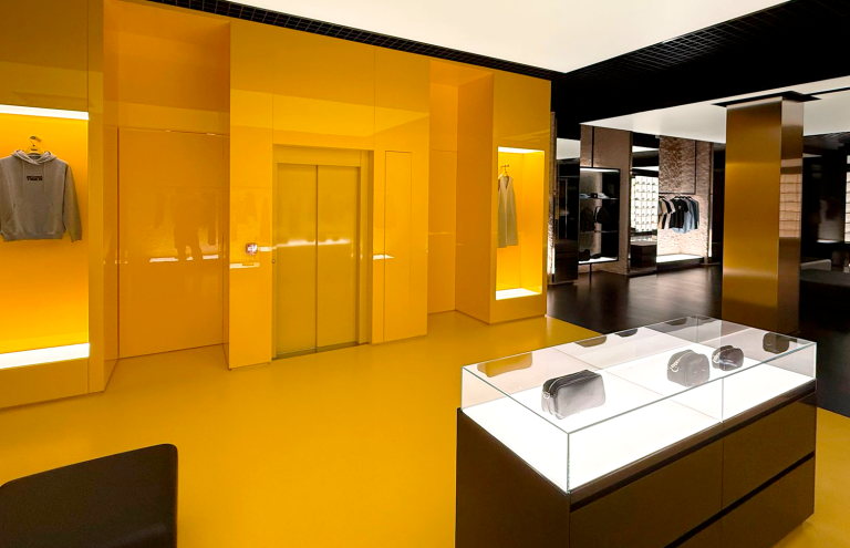 Interior moderno de tienda de ropa con detalles amarillos.