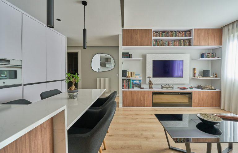 Salón moderno integrado con cocina y estanterías de madera.