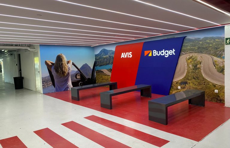 Mostrador Avis y Budget con imagen de carretera y mujer.