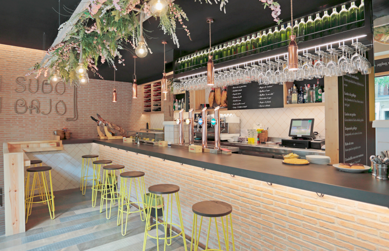 Bar moderno con barra de madera y decoración floral.