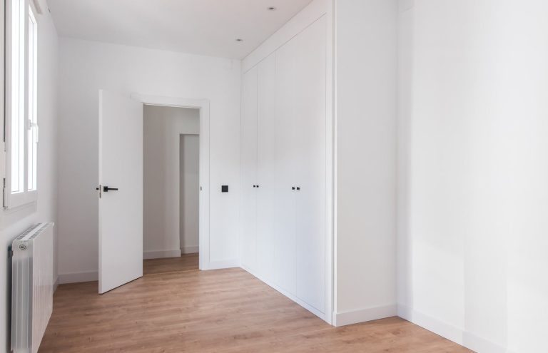 Dormitorio vacío con armarios blancos y suelo de madera.