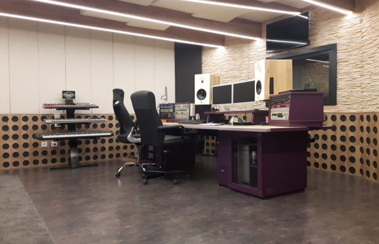 Estudio de grabación profesional con teclado, mesa y monitores.